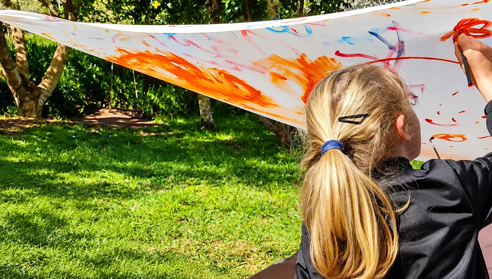 Nena pintando nun pano ao aire libre en Senlleira